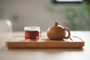 tea pot with glass of red tea on top of chopping board