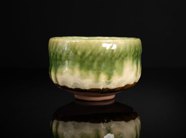 Green ceramic bowl with textured surface on a black background
