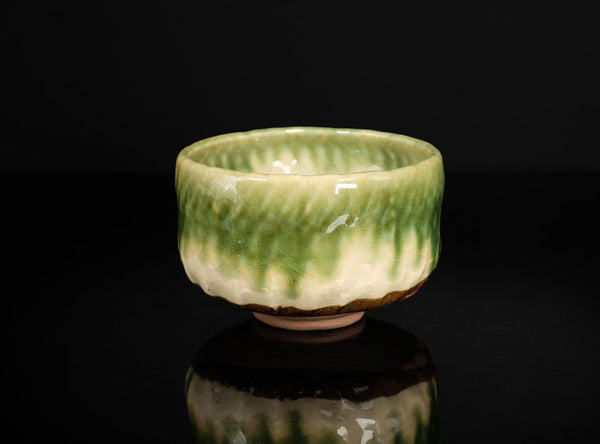 Ceramic bowl with green and white glaze on a black background