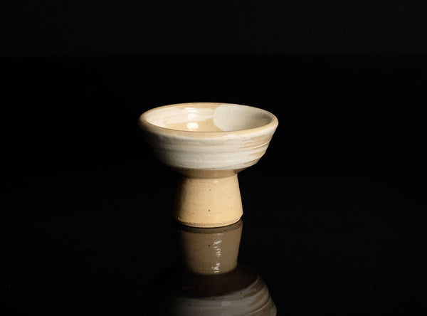 Ceramic sake cup on a black reflective surface