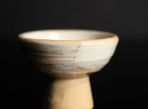 Ceramic sake cup on a black reflective surface