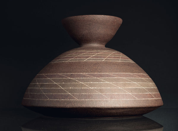 Brown ceramic vase with grid pattern on a black background
