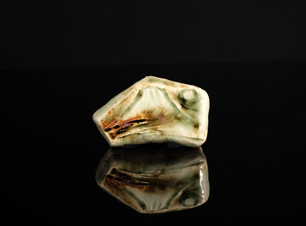 A sculptural ceramic incense box (kōgō) by Ayukai Kōgetsu, modelled in a stylised Mount Fuji form. Its low, angular silhouette combines softly raised contours with flowing cream, olive-green and brown glazes.

The lid rises towards an irregular summit, with sloping sides suggesting the mountain’s distinctive outline. Uneven ridges and gently softened edges give the piece an organic character, interpreting the subject through expressive modelling rather than precise symmetry.
