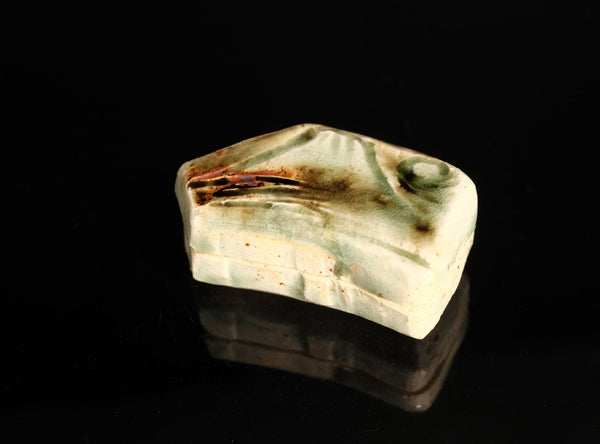 A sculptural ceramic incense box (kōgō) by Ayukai Kōgetsu, modelled in a stylised Mount Fuji form. Its low, angular silhouette combines softly raised contours with flowing cream, olive-green and brown glazes.

The lid rises towards an irregular summit, with sloping sides suggesting the mountain’s distinctive outline. Uneven ridges and gently softened edges give the piece an organic character, interpreting the subject through expressive modelling rather than precise symmetry.