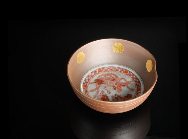 A ceramic bowl with a warm terracotta-colored exterior, decorated with three gold circular accents on the inside rim, and a white interior featuring a red hand-painted dragon motif.