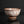 將圖片載入到圖庫檢視器中， A handmade ceramic bowl with a textured, mottled glaze of brown and white, standing on a small footed base against a dark reflective background.
