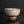 將圖片載入到圖庫檢視器中， A rustic handmade ceramic bowl with a textured, speckled glaze in earthy brown, beige, and gray tones, photographed on a dark reflective surface against a black background.
