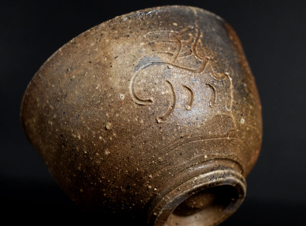 Brown ceramic vase with decorative patterns on a black background