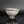 Load image into Gallery viewer, A handmade ceramic tea bowl with a textured, speckled glaze in light gray and brown tones, displayed on a reflective black surface against a dark gray background.
