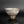 Load image into Gallery viewer, A handmade ceramic bowl with a textured, speckled glaze in earthy beige, brown, and gray tones, set against a dark gray gradient background with a reflective surface below.
