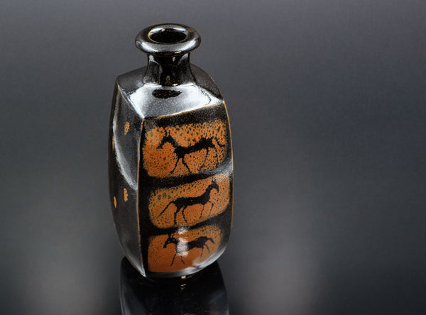 Ceramic vase with black and orange design on a dark gray background
