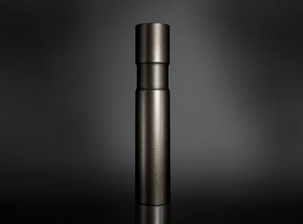 A dark metallic cylindrical flower vase standing upright on a reflective black surface against a dark gray gradient background.