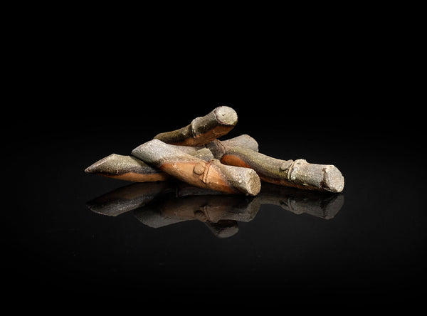 A Set of Five Bizen Chopstick Rests with a metallic sheen on a black reflective surface