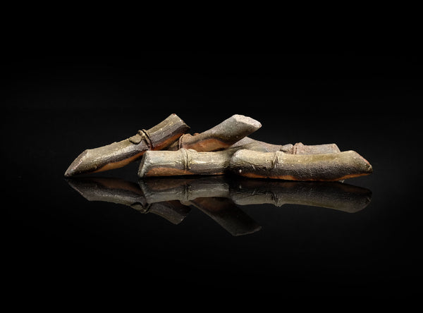 A Set of Five Bizen Chopstick Rests with a metallic sheen on a black reflective surface