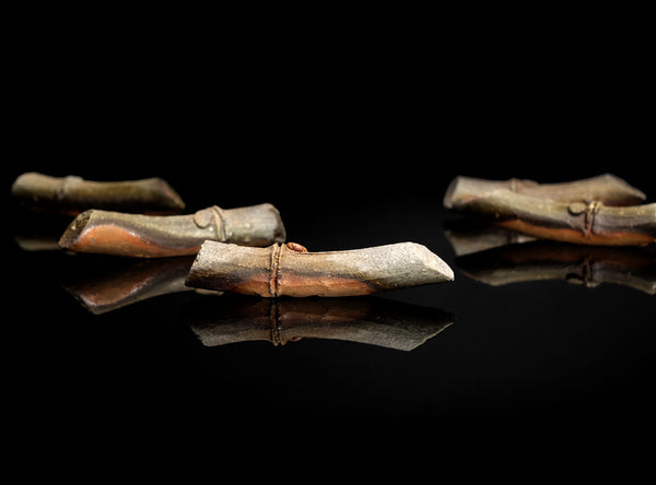 A Set of Five Bizen Chopstick Rests with a metallic sheen on a black reflective surface