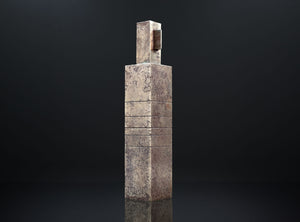 Tall, rectangular stone sculpture on a black background