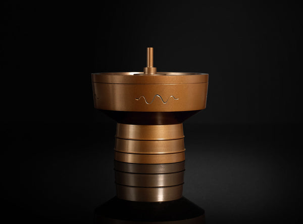 Bronze-colored decorative object with wavy patterns on a black background