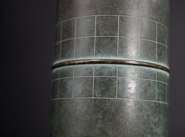 Close-up of a cylindrical metal object with a grid pattern on a dark background