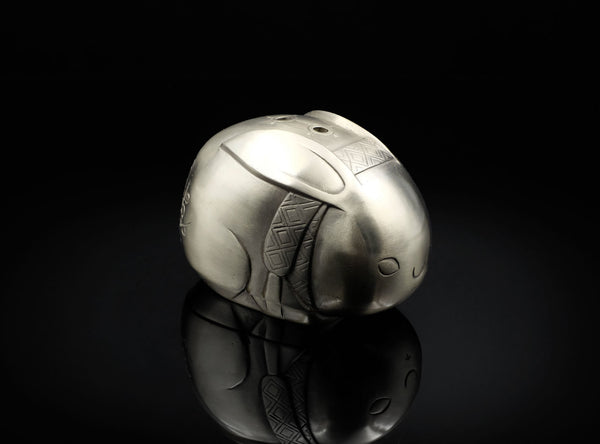 Silver rabbit-shaped object on a black background
