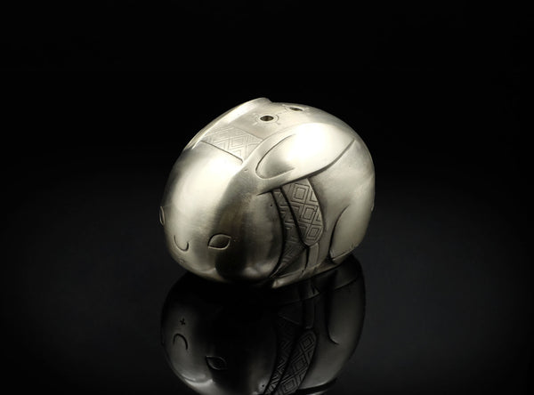 Metallic helmet-like object on a reflective surface with a black background
