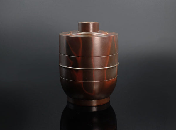A Shudo Bronze Vase with layered design on a dark background