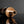 Load image into Gallery viewer, A close-up of a metallic bronze cylindrical object with a circular base and a protruding cylindrical opening, photographed on a dark reflective surface against a dark gray background.
