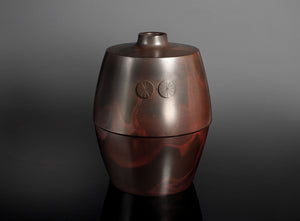 A metallic reddish-brown urn-shaped vase, photographed against a dark gray to black gradient studio background.