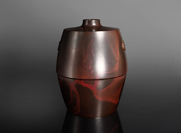 A metallic reddish-brown urn-shaped vase, photographed against a dark gray to black gradient studio background.