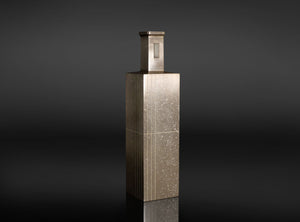 A rectangular metallic box with a textured, brushed silver finish and a small rectangular window on top, set against a dark gray gradient background.