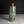 Load image into Gallery viewer, An antique-style cylindrical bronze vase with a green patina and geometric grid engravings, set against a dark gray background.
