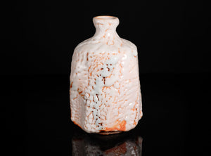Decorative ceramic bottle with textured surface on a black background