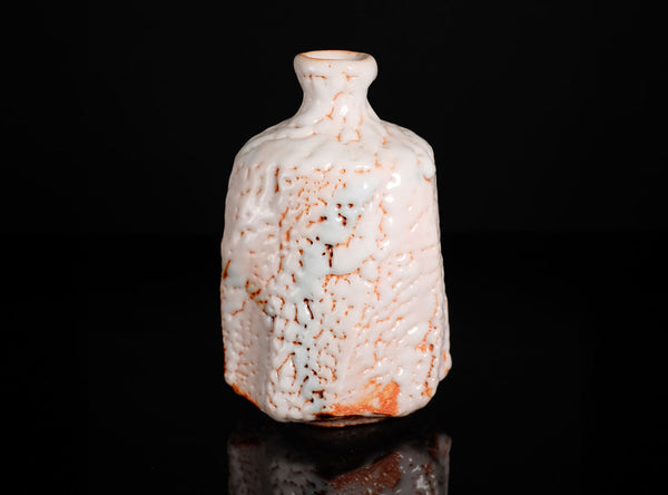 Decorative ceramic bottle with textured surface on a black background