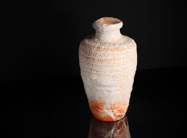 Ceramic vase with orange and white glaze on a black background