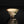 Load image into Gallery viewer, A small ceramic footed bowl with a cream-colored glaze, decorated with brown floral patterns and green accents, set against a dark gray gradient background with a reflective surface below.
