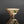Load image into Gallery viewer, A small ceramic footed bowl with a cream-colored glaze, decorated with brown floral patterns and green accents, set against a dark gray gradient background with a reflective surface below.
