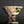 Load image into Gallery viewer, A handmade ceramic footed bowl with a textured off-white glaze, decorated with brown brushstrokes and green accents, set against a dark gray background with a soft reflection below.
