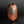 Load image into Gallery viewer, A small organic-shaped ceramic vase with a wide opening, featuring a mottled finish that transitions from dark brown to warm terracotta orange, set against a dark gradient background.
