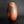 Load image into Gallery viewer, A small organic-shaped ceramic vase with a wide opening, featuring a mottled finish that transitions from dark brown to warm terracotta orange, set against a dark gradient background.
