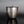 Load image into Gallery viewer, A metallic cylindrical container with a ribbed textured surface and a matching lid featuring a small loop handle, set against a dark gray gradient background with a reflective black surface below.
