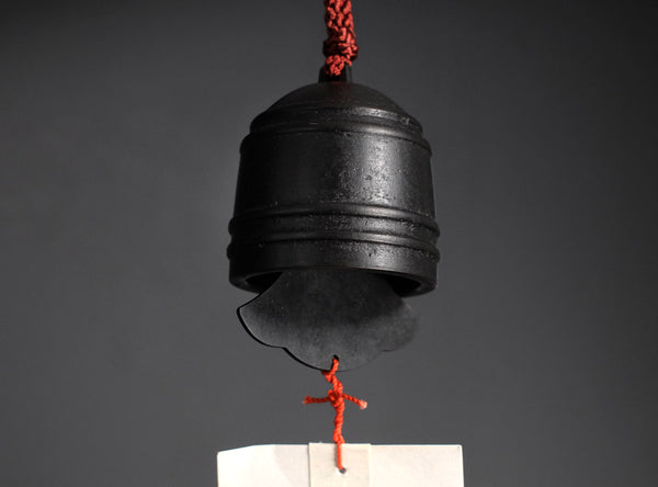 A finely crafted sahari wind bell, A hanging calligraphy brush with a black ink stick, red cord, and long white paper brush stroke featuring black calligraphy characters, set against a dark gray background.