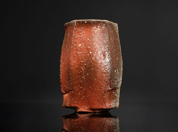 Cylindrical ceramic cup with a textured surface on a black background