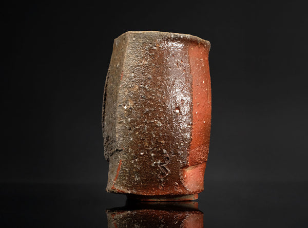 Cylindrical ceramic cup with a textured surface on a black background