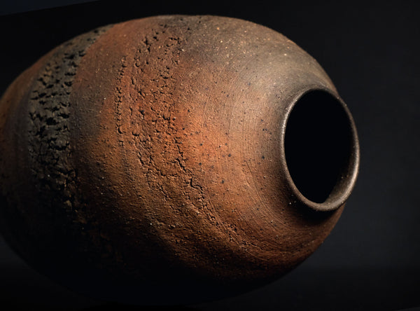 Rust-colored ceramic vase on a black background