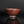 將圖片載入到圖庫檢視器中， A handmade ceramic tea bowl with a textured, earthy reddish-brown glaze, shown on a reflective dark surface against a solid black background.
