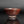 將圖片載入到圖庫檢視器中， A handmade ceramic tea bowl with a textured, earthy reddish-brown glaze, shown on a reflective dark surface against a dark gray background.
