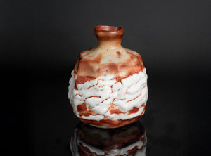 Decorative ceramic vase with white and brown glaze on a dark background