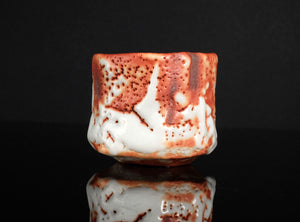 Ceramic mug with red and white glaze on a black background