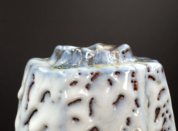 Ceramic vase with textured surface on a dark background