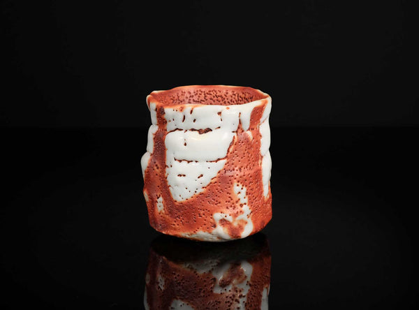 Ceramic cup with red and white pattern on a black background