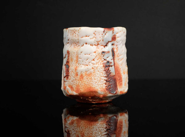 Ceramic cup with textured surface on a black background